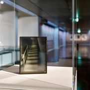 Ausstellungsansicht "Richter/Polke". Detail des Werkes "Kugelobjekt, Ateliertreppe I" von Gerhard Richter aus dem Jahr 1970. Das Werk besteht aus Holz, Glas, Metall, Fotopapier und Farbe. Man sieht ein Foto einer Treppe, gerahmt in einer Metallkasten.
