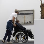 Person im Rollstuhl und eine zweite Person betrachten eine Skulptur.